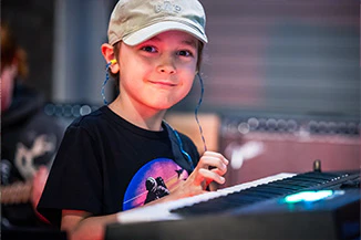 School of Rock after-school student playing piano and smiling