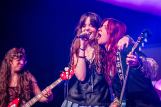 Two students sharing the stage, harmonizing together into the same microphone.