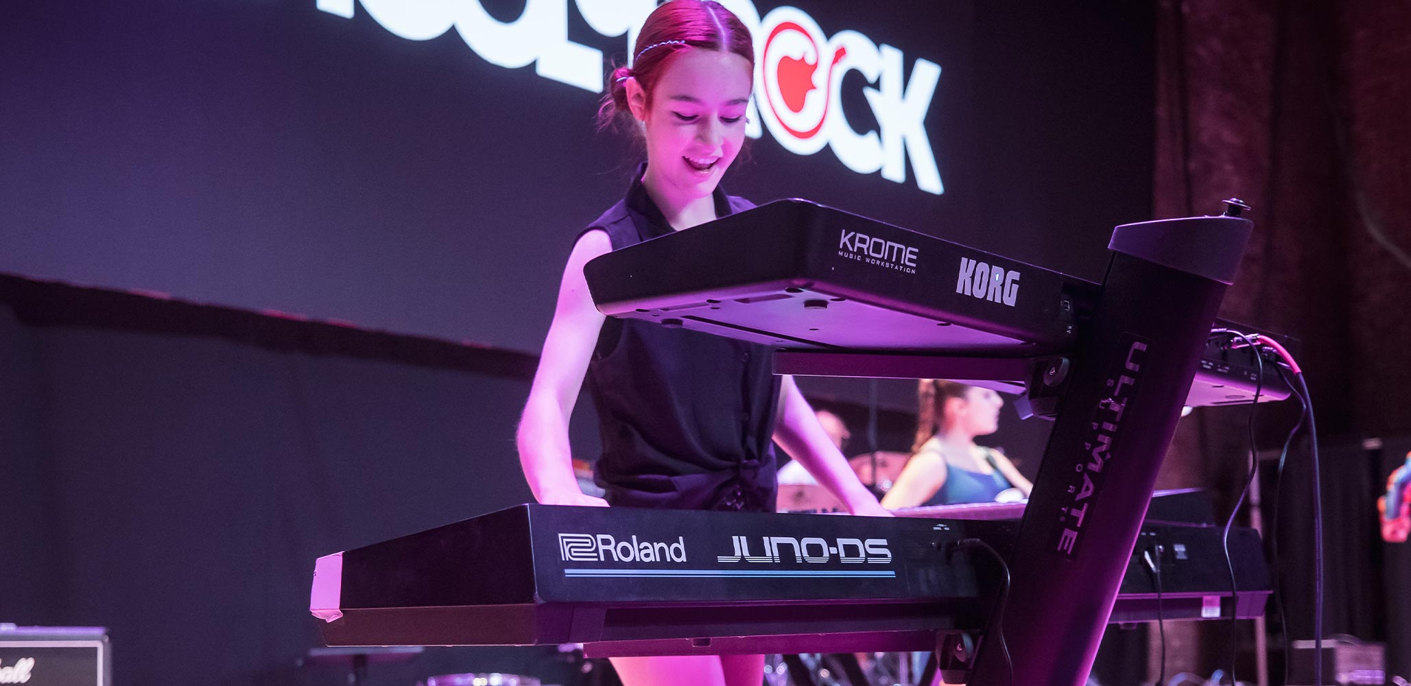 School of Rock student smiling while performing keys on stage
