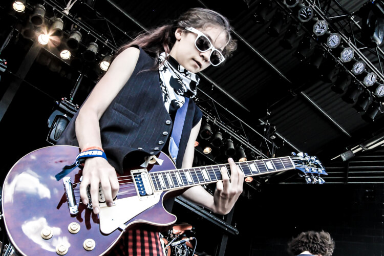 Young girl playing the electric guitar on stage