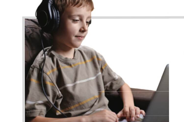 Kid listening with headphones typing on computer