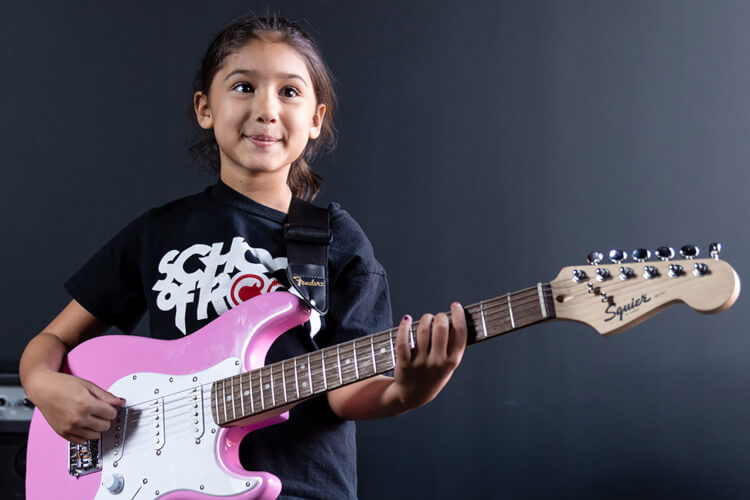 Young girl holding a pink guitar