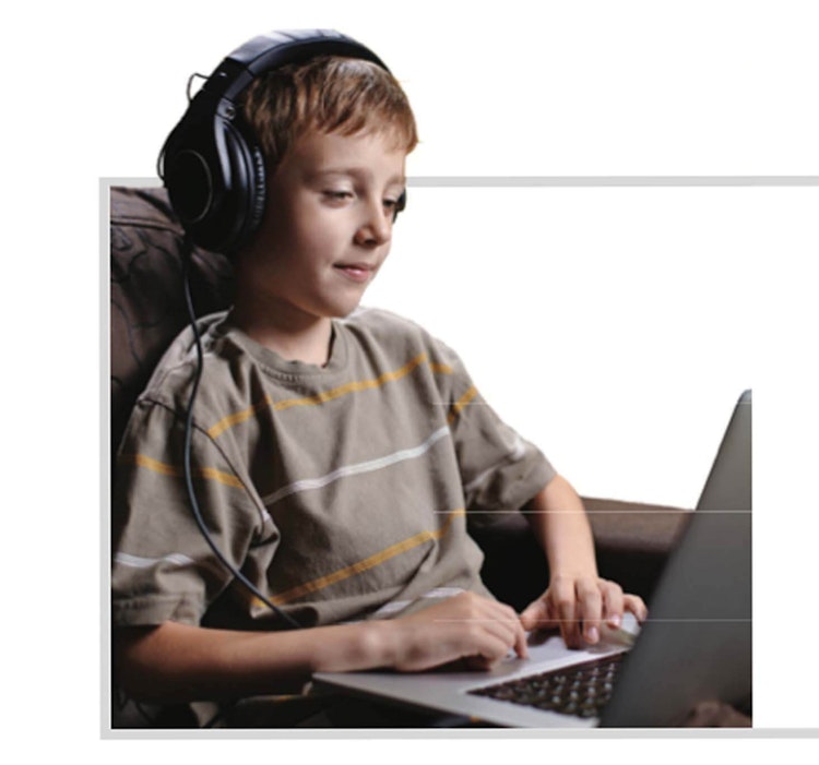 Kid listening with headphones typing on computer