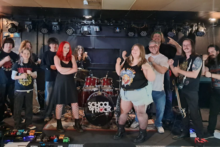 School of Rock York's House Band poses with their teachers on stage