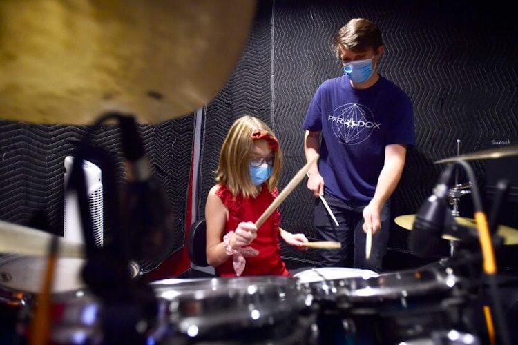 School of rock teacher practices drums with student