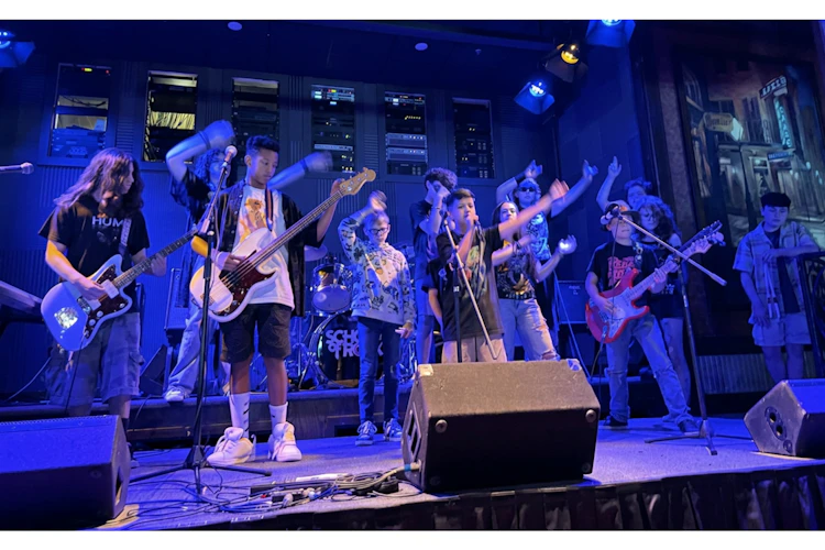 School of Rock students on stage waving to crowd