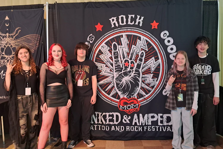 School of Rock York's House Band poses in front of the Inked & Amped event banner