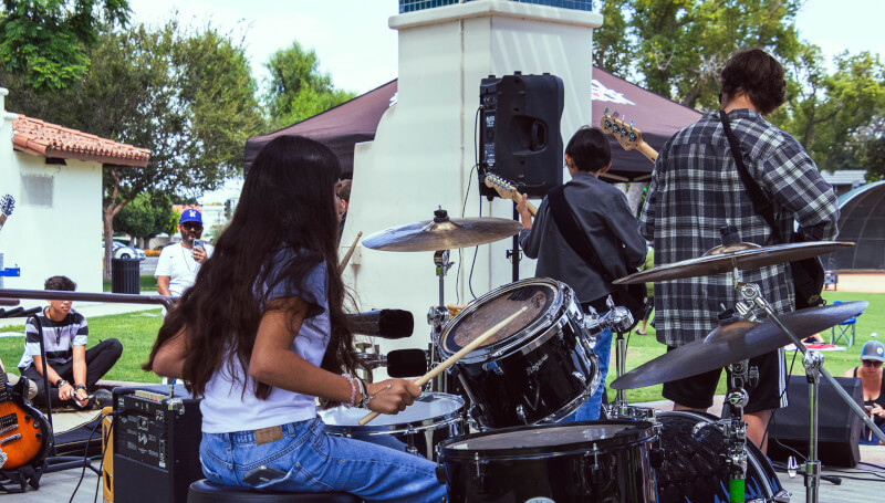 A drummer performs on stage, photo taken from behind the drum set.