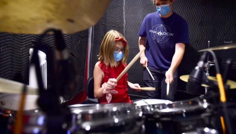 School of rock teacher practices drums with student