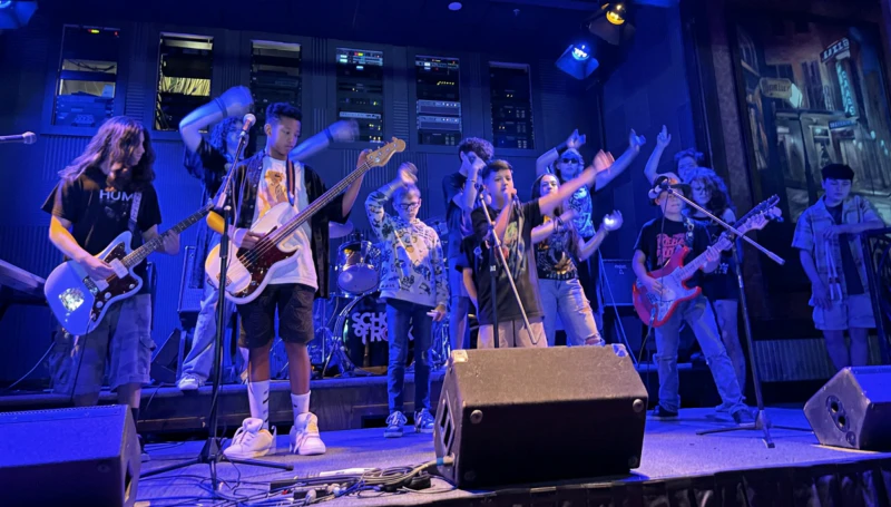 School of Rock students on stage waving to crowd