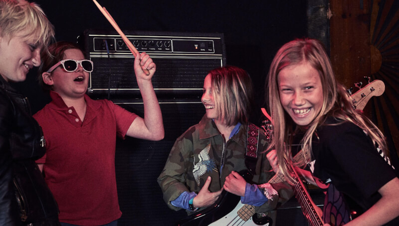 A group of School of Rock students smile in group music lessons