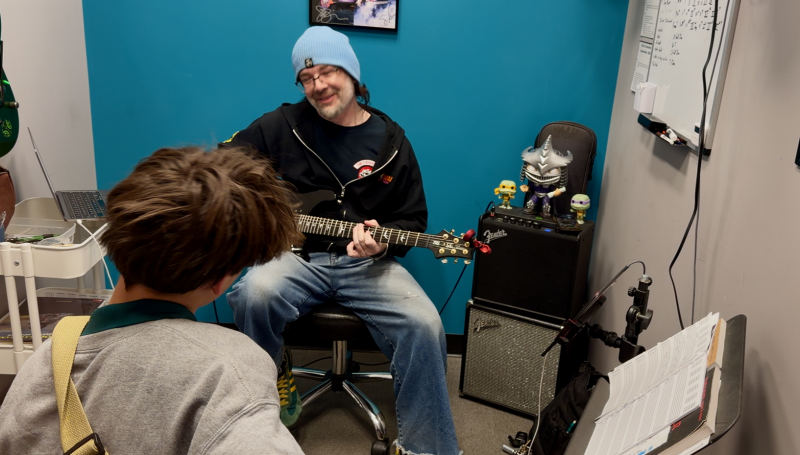 Student learning guitar during a music lesson demonstrating the benefits of music education