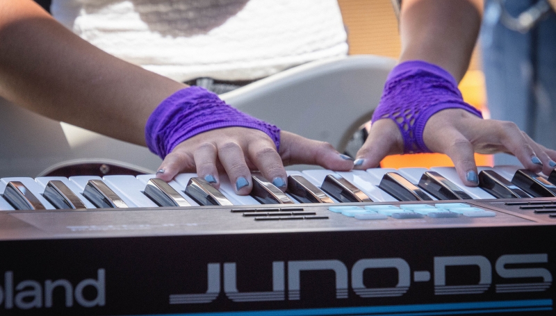 A student wearing purple mesh gloves plays an electric keyboard.