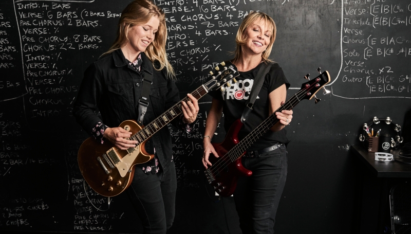 Profesora de guitarra le da una lección práctica a su alumna adulta en Adult Performance At Noon, clases de instrumento al medio día en School of Rock Pedregal, la mejor escuela de música de México.