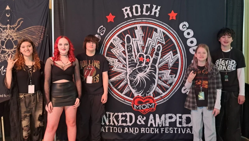 School of Rock York's House Band poses in front of the Inked & Amped event banner