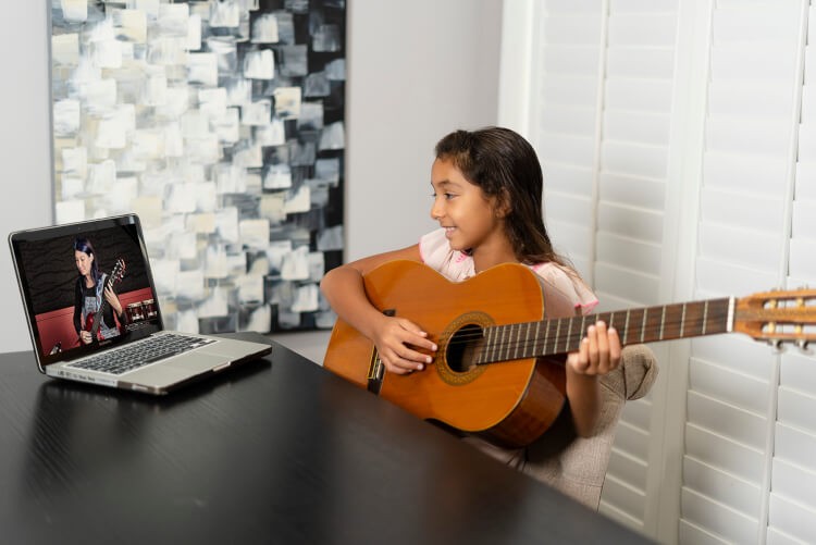 Student learning to play in online rock program for kids