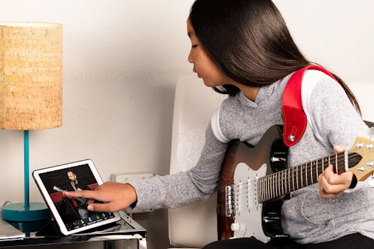 Chica usando un iPad durante su clase de guitarra on-line
