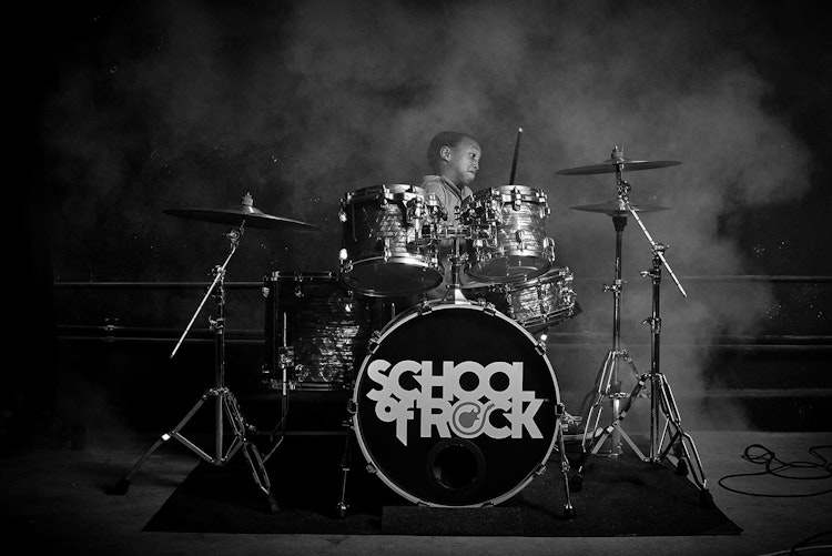 Alumno de la School of Rock tocando la batería en el programa de música Rookies para alumnos de primer grado
